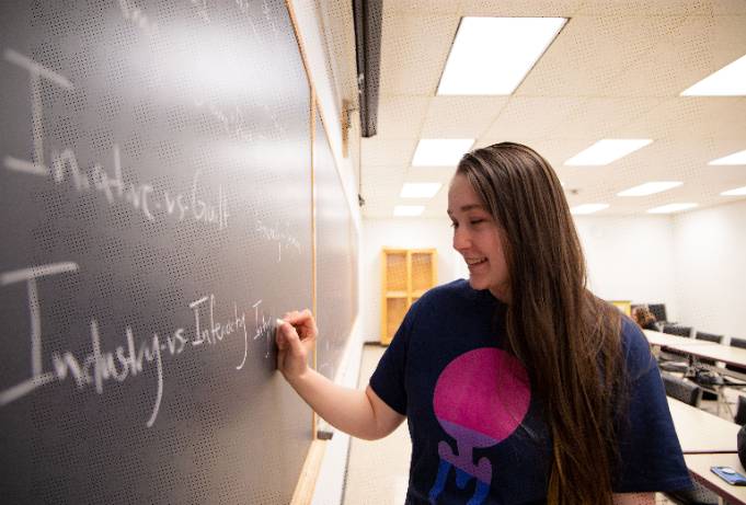 female student writes on whiteboard